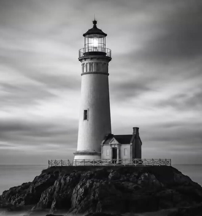 A lighthouse shining on a rocky point at dusk, a steady light pointing the way forward